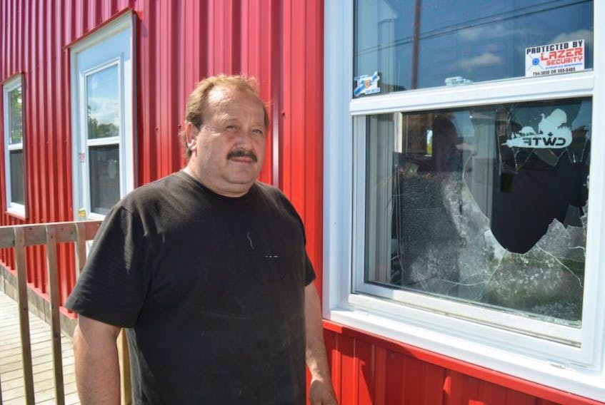 Freddie Anderson, owner of Sam’s Auto Glass in North Sydney, stands by a broken window at his business on King Street on Tuesday. Between 8 p.m. on Monday and 7:30 a.m. on Tuesday, someone broke into the local business, stealing the company’s computer as well as a window screen.