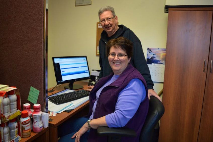 Sharon MacLean, chair of the Sydney Mines Food Bank Society, and volunteer Wilson Carey insert information into the new computer system purchased through a grant.