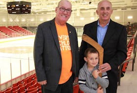Stewart Matheson, right, poses with his grandson, Cailex Tournidis, and Membertou First Nation Chief Terry Paul, at the Membertou Sport and Wellness Centre after the century-old hockey stick owned by Matheson’s family was donated to Membertou Heritage Park last week.