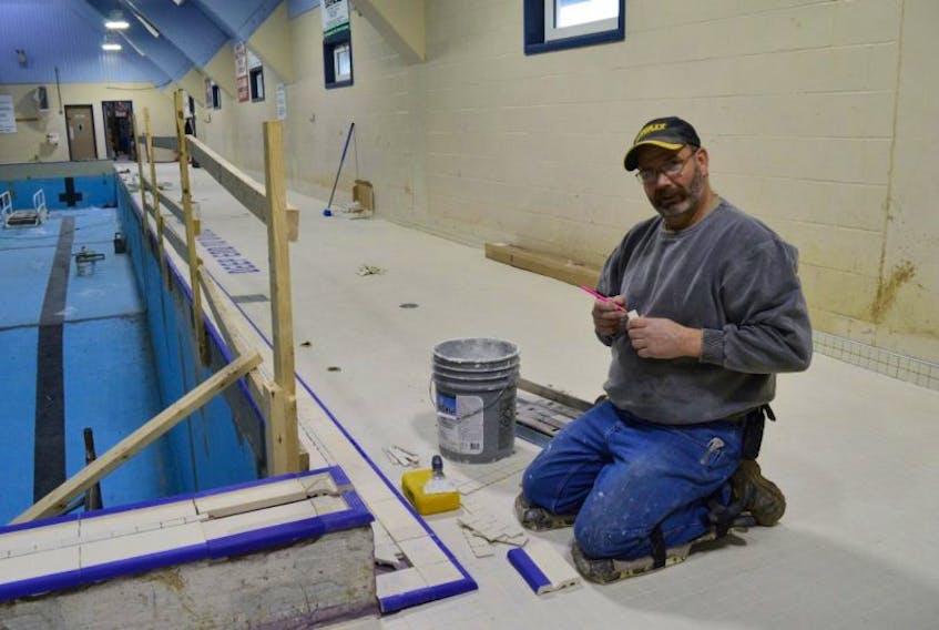 Lindsay Sampson with Taylor Flooring installs tiles along the deck of the Northside Community Pool.
