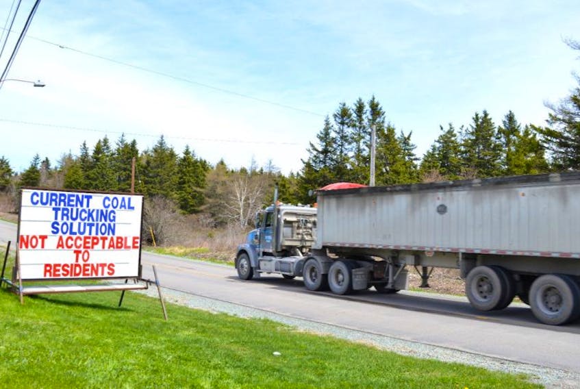 A coal truck heading to the Donkin Mine travels down the Long Beach Road in Port Morien, past a protest sign Claude Peach has set up on his front lawn. Port Morien residents are concerned over the heavier traffic and the safety of the children.