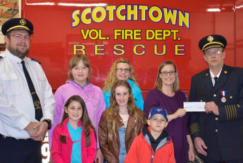 Laurie Gardiner, back right, of Gardiner Mines, accepts a cheque for $1,000 from Chief Raymond Eksal of the Scotchtown Volunteer Fire Department. The money will be used to purchase an automated external defibrillator for Greenfield School in River Ryan. Taking part in the presentation were from left, front, students Taylor Hurley, Elise Turner, Jaxson Gardiner and in back, Ashley Osborne, deputy fire chief, and Maggie MacNeil and Erin Turner of the Greenfield Home and School Association.