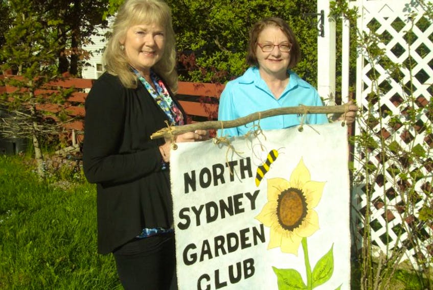 Patsy MacKenzie, past president of the NSAGC, and Dona Benac, president of the North Sydney Garden Club, holding the North Sydney Garden Club banner.