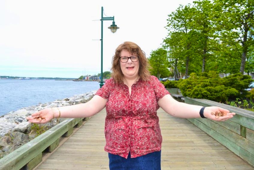 Suzanne Spencer, a native of Glace Bay who now lives in Sydney, is seen here on the Sydney boardwalk with a handful of pennies. Spencer, who believes in the luck of a penny, has distributed 150 pennies around the Cape Breton Regional Municipality in celebration of Canada 150.