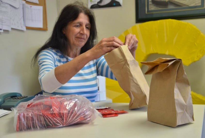 Christine Porter, executive director for the Ally Centre of Cape Breton, puts condoms in bags for people to take for free. She is urging people to always use condoms to help stop the spread of sexually transmitted infections.