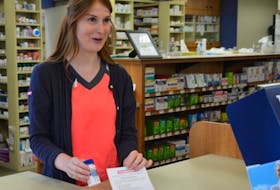 Amanda Burke, pharmacy assistant at Membertou Pharmasave, sells Tylenol 1 with an information sheet to a client.