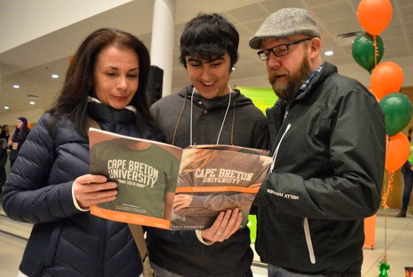 Trevor Boudreau, centre, looks over some information with his mother Raylene Stephens and stepfather Bernie MacIntosh during CBU 101 at the Cape Breton University’s Verschuren Centre on Tuesday night. The event for high school students and their parents included a campus tour and information on financial aid and scholarships.