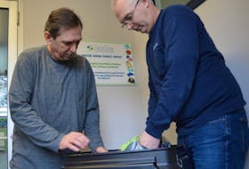 Seaside employees Tony O’Brien and Steve Currie look through some clothing donations they’ve gathered for flood victims. People are encouraged to drop donations at their Grand Lake Road location.