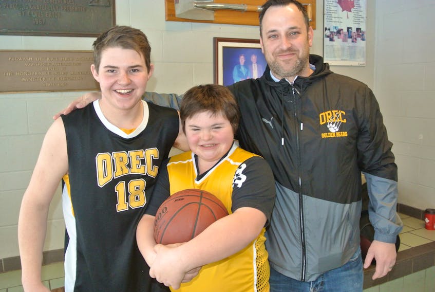 Seven Rushton, centre, is shown with his teammate and brother, Riley, and coach Oxford Regional High School Golden Eagles coach Mike Hudson before a recent high school boy’s basketball game. Seven, who has Down Syndrome, took to the court for the first time in a recent game and scored a pair of baskets. Darrell Cole – Amherst News