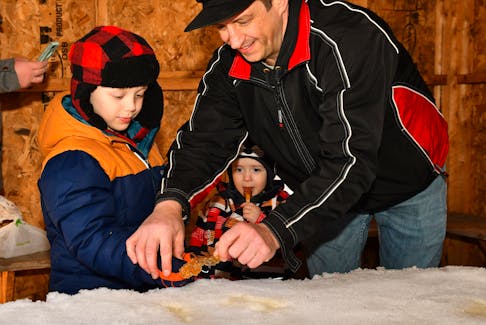 Evan Jardine helps his kids, six-year-old Emmerson and two-year-old Eli, scoop maple syrup from the snow at the Donkin’s Maple Sugar Woods. The Jardines live in Springhill. DAVE MATHIESON – AMHERST NEWS
