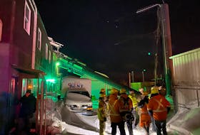 Firefighters and other personnel stand in front of a snapped-off cellphone tower in St. John’s Friday night. A 30-metre section of the tower, visible at left, fell onto St. Pat’s Bowling Lanes. No one was injured. KEITH GOSSE/THE TELEGRAM