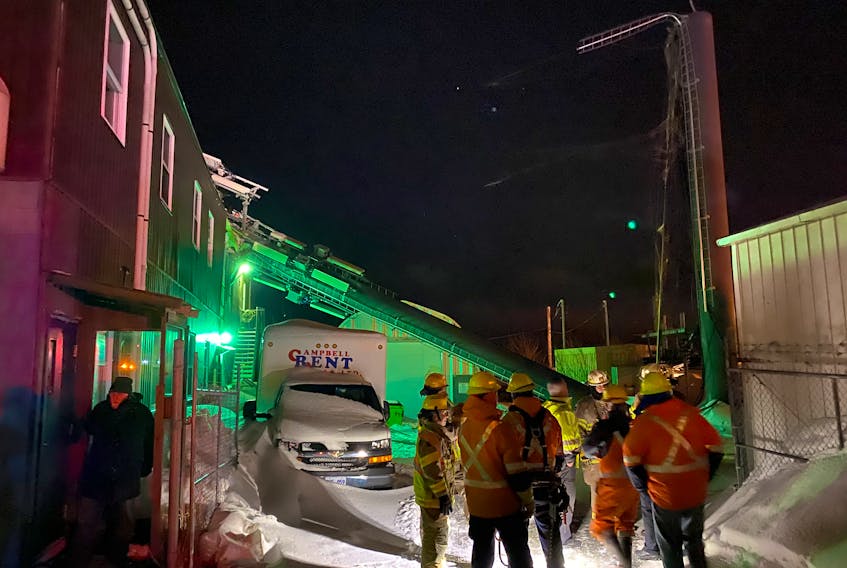 Firefighters and other personnel stand in front of the snapped-off cellphone tower when it collapsed Feb. 28. A 30-metre section of the tower, visible at left, fell onto St. Pat’s Bowling Lanes. No one was injured. -TELEGRAM FILE PHOTO
