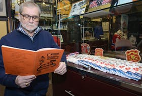 Allan O’Keefe looks through the first program from the Spud Minor Hockey Tournament. Jason Malloy/The Guardian