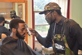 Luke Ignace, right, has opened a barbershop on Victoria Row in Charlottetown that aims to create conversation and opportunities among the Black community but is open to everyone. Here he gives his friend, Loki, a trim.