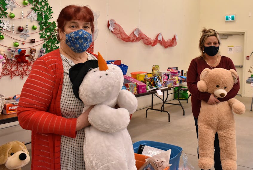 Founder Betty Begg-Brooks, left, and volunteer April Stevenson hold two giant stuffed plushies in front of the table of toys at the new temporary location for Gifts from the Heart on Jordan Crescent which was given to the organization completely for free.