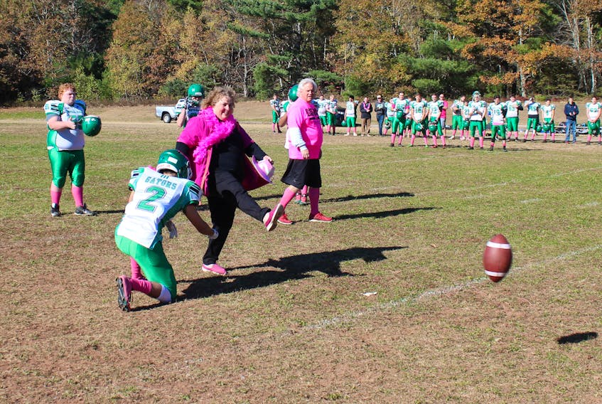 Jill Conrad-Tracey kicks off the ceremonial first ball during a recent Central Kings football game to help mark a game dedicated to breast cancer.