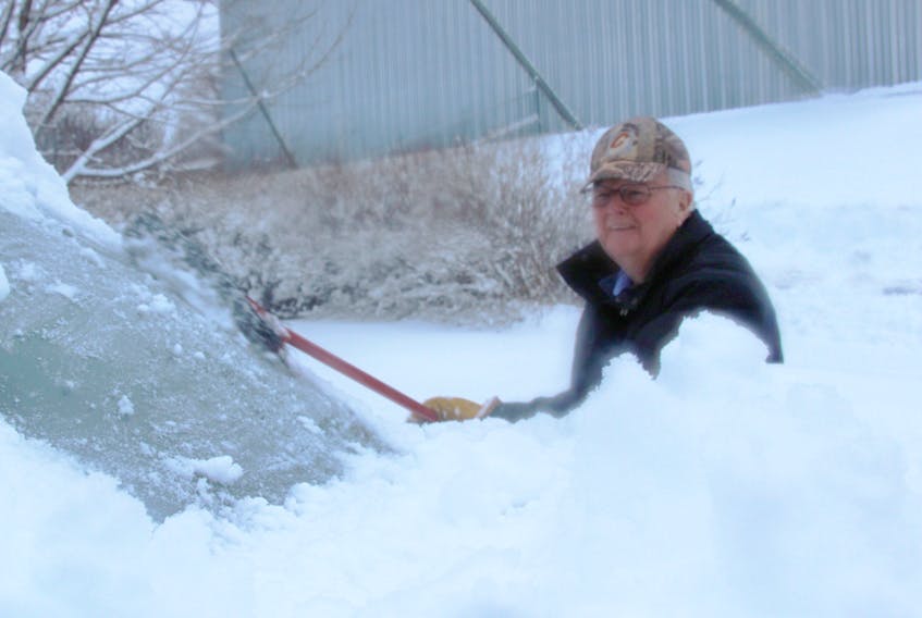 Owen MacDonald of Pictou cleans some of the surfeit of snow that fell on Wednesday night from the windshield of his truck.