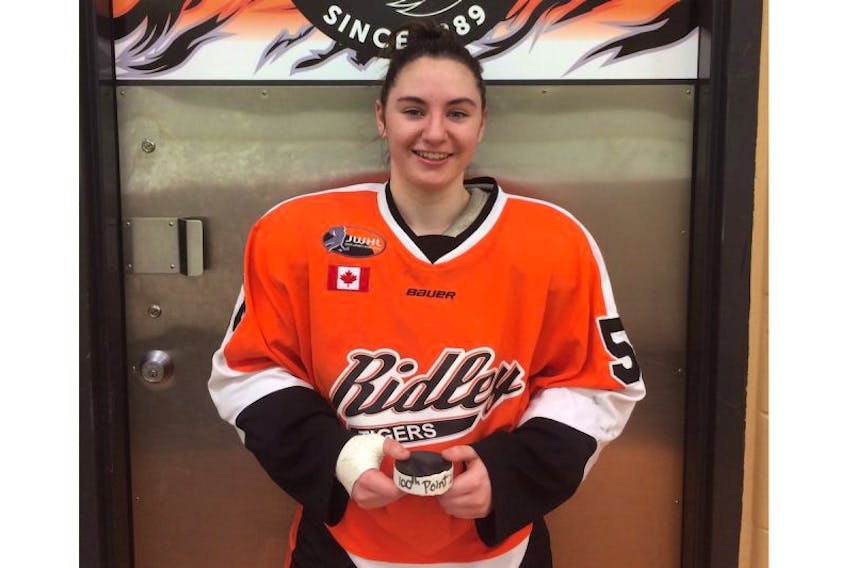 Ridley Tigers forward Shailynn Snow displays a puck honouring her 100th point of the year playing for the prep school in St. Catherines, Ont.