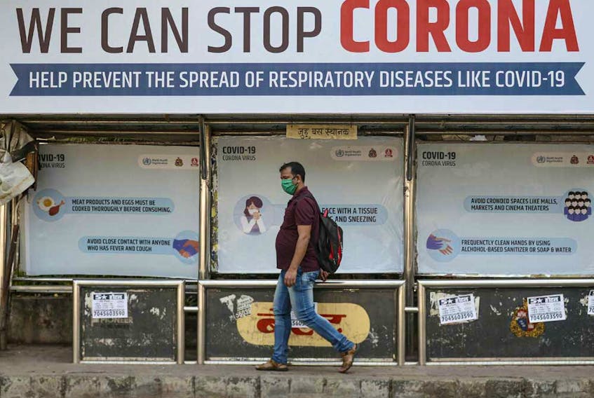 A man wearing a protective mask walks past a bus stop displaying preventive measures against the coronavirus in Mumbai, India.