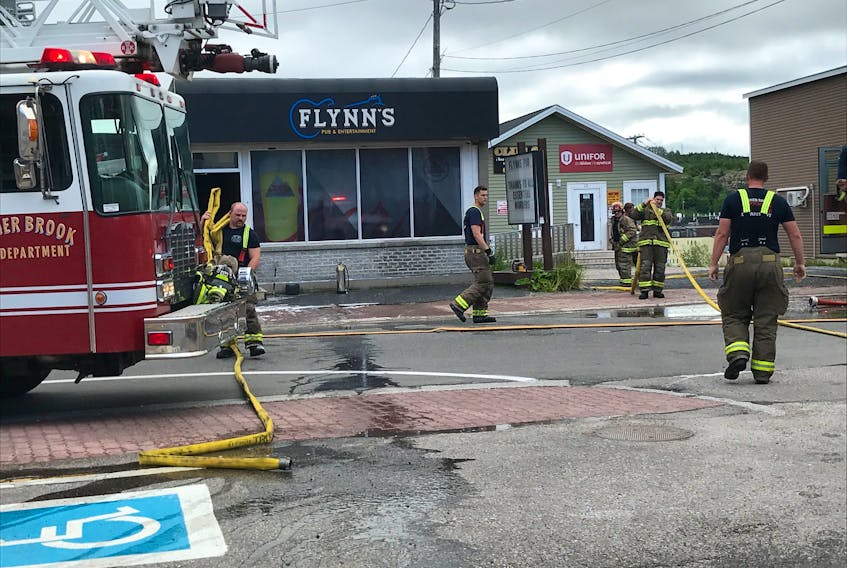 Firefighters with the Corner Brook Fire Department cleanup outside Flynn’s Pub on Broadway after extinguishing a fire there Tuesday morning.