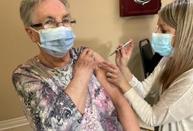 Emma Miller, a resident of Mountain View Retirement Centre in Corner Brook, is injected with the first dose of a COVID-19 vaccine by public health nurse Joy Green.