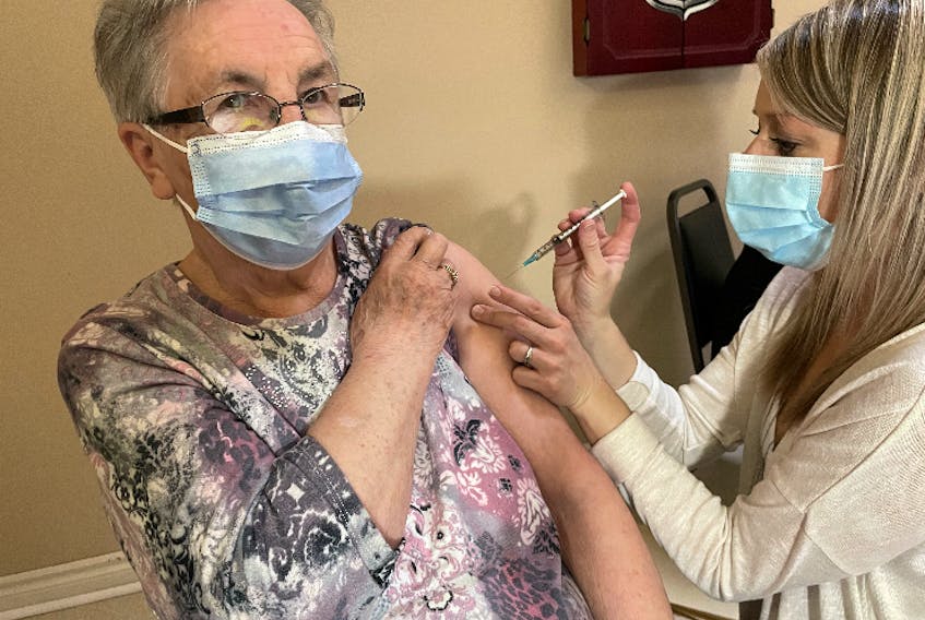 Emma Miller, a resident of Mountain View Retirement Centre in Corner Brook, is injected with the first dose of a COVID-19 vaccine by public health nurse Joy Green.