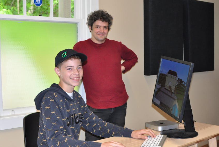 Max Pittman, seated, is the moderator for the Graham Academy’s Virtual Corner Brook program. Reg Kachanoski, Gros Morne Summer Music’s company manager, developed the program that will see students from kindergarten to Level 3 build Corner Brook in Minecraft.