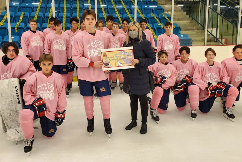The Joneljim Cougars of the Nova Scotia Under-15 Major Hockey League donated $2,800 to the Cape Breton Cancer Patient Care Fund recently. Usually the team holds a Pink in the Rink game to raise money to the fund, however, this year’s game was cancelled due to the COVID-19 pandemic. Cougars captain Tyler Seymour, centre, presents the cheque to Lisa Sinclair on behalf of the team for the patient care fund. CONTRIBUTED • ANGIE MACDONALD