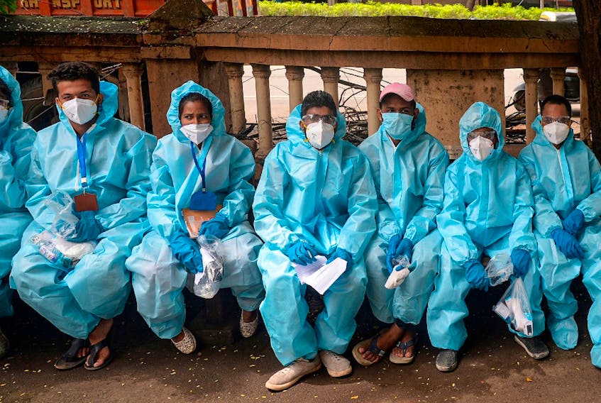 Health workers wearing Personal Protective Equipment (PPE) wait for instructions to conduct a door-to-door medical screening drive for COVID-19 coronavirus, at a residential area in Mumbai on July 20, 2020.