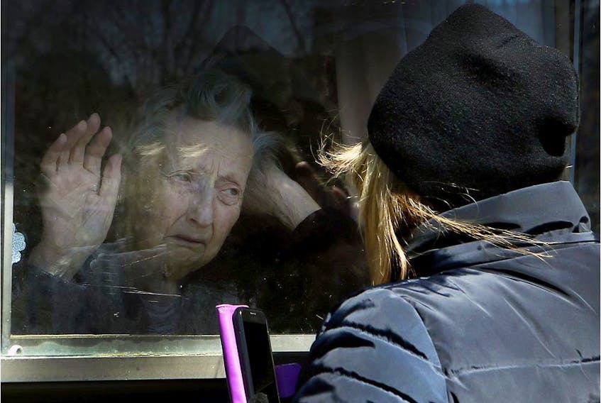 A woman visits her 86-year-old mother through a window at the Orchard Villa long-term care home in Pickering on Wednesday April 22, 2020. The Pickering home was one of the homes included in a shocking report by the Canadian military, released Tuesday by the province, regarding the status of five homes in Ontario. 