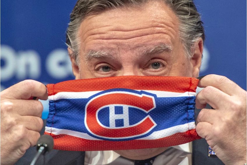 Quebec Premier François Legault puts on a Canadiens mask as he finishes the daily COVID-19 news briefing in Montreal on May 21, 2020.