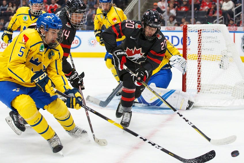 Canada's Dylan Holloway (20) battles Sweden's Alexander Lundqvist (5) for puck possession during the Hlinka-Gretzky Cup gold medal game in Edmonton on August 11, 2018.