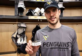 Pittsburgh Penguins centre Sidney Crosby shows the puck he used to record his 1,300th NHL point on Thursday against the Buffalo Sabres.