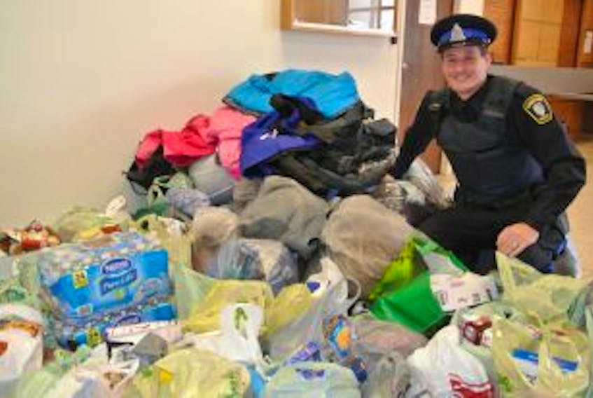 ['The Amherst Police Department’s crime prevention officer Const. Tom Wood looks over some of the items collected during the Cram the Cruiser event late last week. Students at Spring Street Academy, West Highlands Elementary and E.B. Chandler Junior High and shoppers at Sobeys and Walmart filled the community policing cruiser twice with food and winter clothing.']