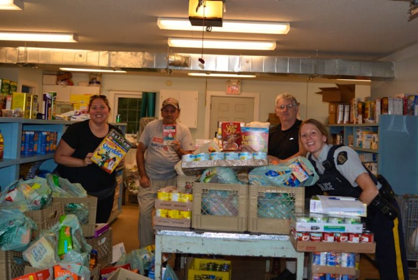 <p>Michelle Parker (Kings County Senior Safety), Upper Room Food Bank volunteers Roger Penny and Harley Hazelwood and Kings District RCMP Const. Kelli Gaudet gather around donations collected during a recent Cram the Cruiser event held in support of the food bank.</p>