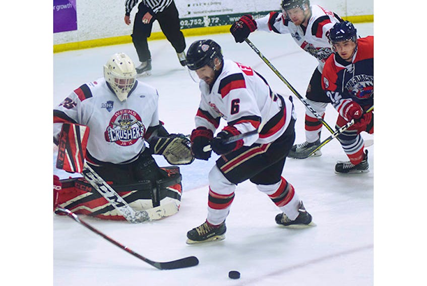Crushers’ defenceman Aleck Forcier tries to clear a loose puck in front of netminder Matt Normore on Thursday.