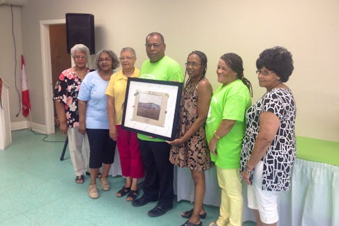 A committee of volunteers from the Wallace Lucas Community Centre are pictured with a piece of artwork that includes the names of all the teachers who worked at the former school.