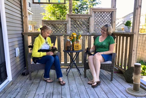 Marie Leloup, left, and Cindy Murphy, organizers of an upcoming tour of outdoor cat enclosures in Halifax, relax in one Leloup had added to her home last year with her kitty Gucci. The catio tours are being organized by the Tuxedo Party to spread the word about options for kitties who want to enjoy the outdoors in a protected setting.