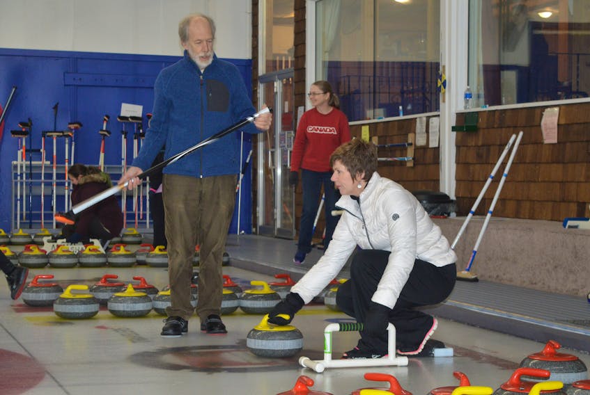 Cynthia Boutilier is taught how to curl from Ron Labelle during the Taste of Winter: Learn to Curl event at the Sydney Curling Club on Saturday.