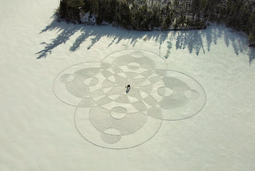 Sheldon Benoit and Matt Robinson stand in the centre of a snow circles design they made using snowshoe prints at MacElmonds Pond in Debert, N.S.