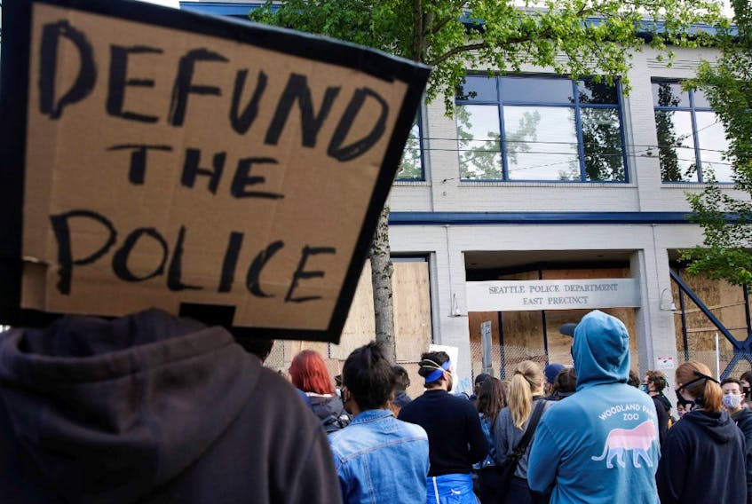  A protester holds a sing that reads “defund the police” after Seattle Police vacated the department’s East Precinct and people continue to rally against racial inequality and the death in Minneapolis police custody of George Floyd, in Seattle, Washington, U.S. June 8, 2020.