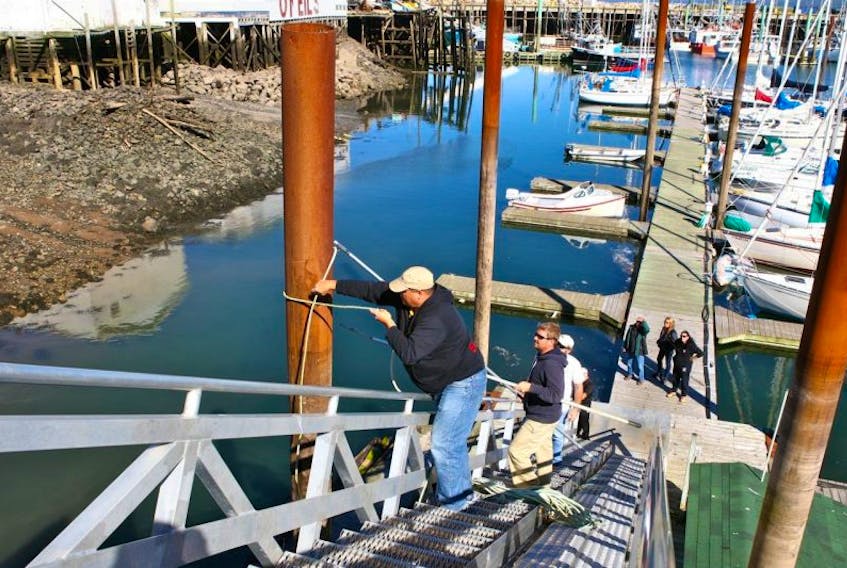 <p>Boat owners Mike Carter, top, and Colin Bondy lash a steel support pylon, hoping to guide its swaying.</p>