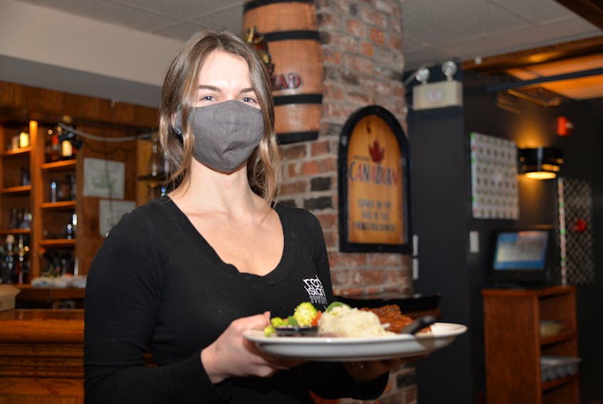 Bailee Payne, a server at Hunter's Ale House in Charlottetown, serves up an afternoon meal for a customer on Friday. Dining rooms were allowed to reopen Friday after being closed on Dec. 6 as part of the circuit breaker measures.