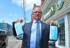 Scott MacVicar, owner of Spinner’s Men’s Wear on Charlotte Street in Sydney, holds up masks stocked at his store, in preparation for masks becoming mandatory in indoor public places in Nova Scotia today. Some businesses in the Cape Breton Regional Municipality are expressing concerns over what to do if someone does enter their business without a mask on. Sharon Montgomery-Dupe/Cape Breton Post