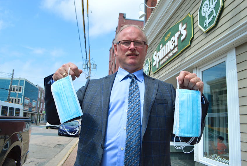 Scott MacVicar, owner of Spinner’s Men’s Wear on Charlotte Street in Sydney, holds up masks stocked at his store, in preparation for masks becoming mandatory in indoor public places in Nova Scotia today. Some businesses in the Cape Breton Regional Municipality are expressing concerns over what to do if someone does enter their business without a mask on. Sharon Montgomery-Dupe/Cape Breton Post