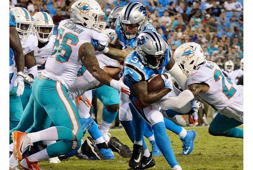 Carolina Panthers' Cameron Artis-Payne (34) runs through Miami Dolphins' Quincy Redmon (66) and Torry McTyer (24) for a touchdown in the second half of a preseason NFL game in Charlotte, N.C., in this file photo from Aug. 17, 2018.
