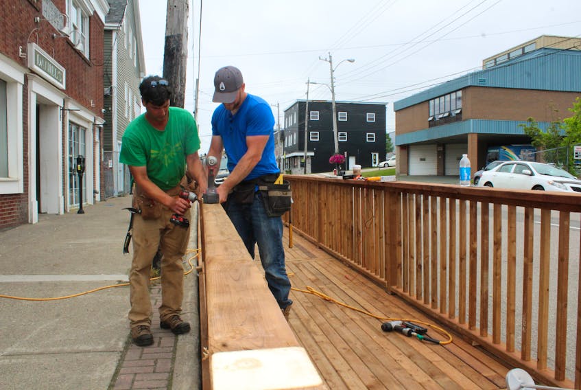 Mark Anderson, left, and Greg Huestis of Jeff Ellis Enterprises put the finishing touches on a new deck at Daniel’s Alehouse and Eatery. The deck sits outside the main entrance to the Charlotte Street, Sydney establishment and will add to the outdoor dining options for the alehouse as well as help meet social distancing measures put in place by the province in the battle against COVID-19. It was expected to be ready for diners by today. GREG MCNEIL • CAPE BRETON POST