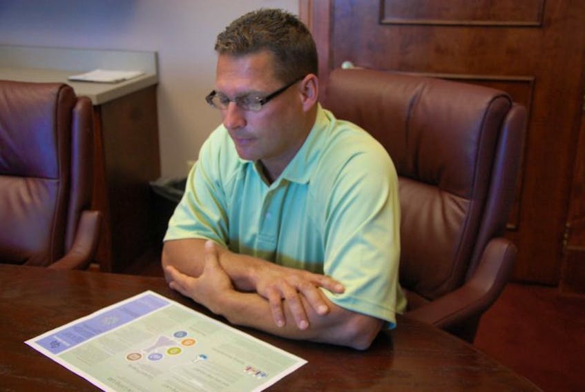 <p>Summerside economic development director, Mike Thususka, looks over an outline on the city’s long-term plan for development. Part of that plan includes and eco industrial park which is under development.</p>