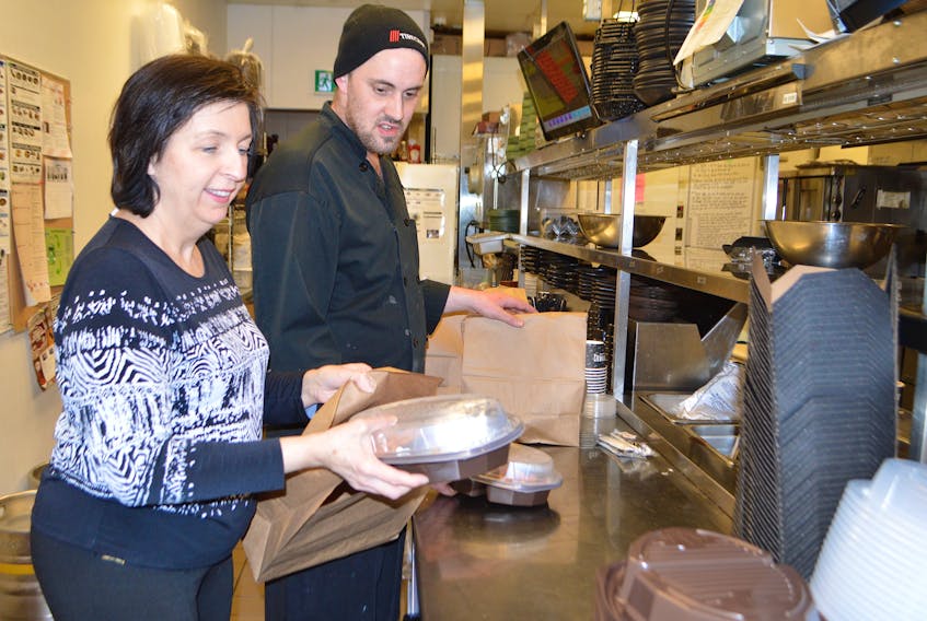 Flo Fogarty, manager of Montana’s restaurant on Reeves Street in Sydney, and Logan MacDonald, kitchen manager, work on putting some takeout orders together at the restaurant. Sharon Montgomery-Dupe/Cape Breton Post