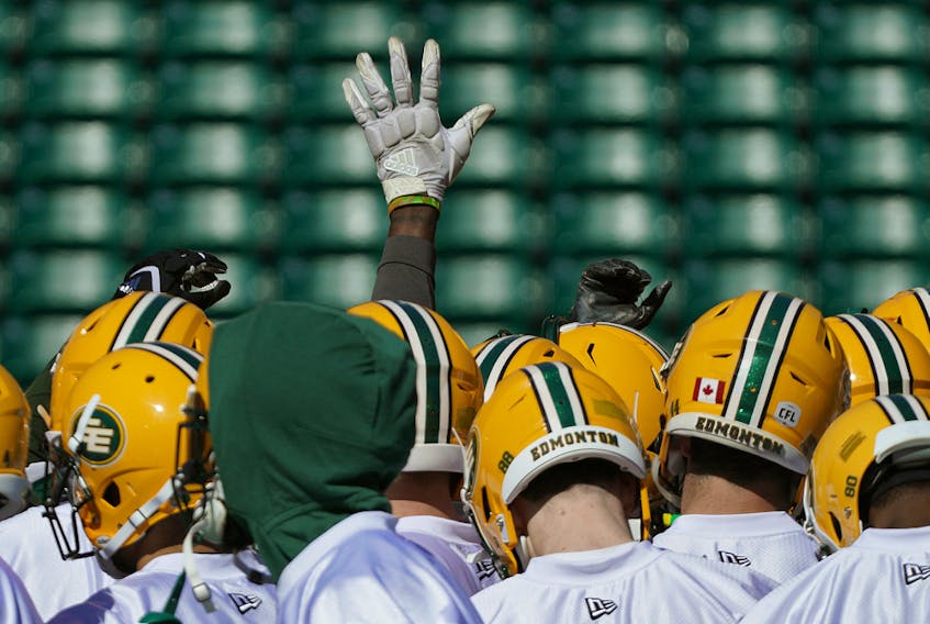 A lone hand is raised during a team huddle during training camp for the Edmonton Football Club at Commonwealth Stadium on May 20, 2019.